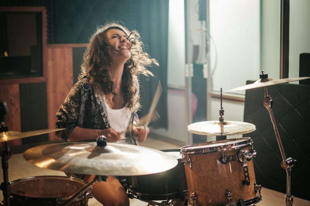 Woman playing drums during music band rehearsal