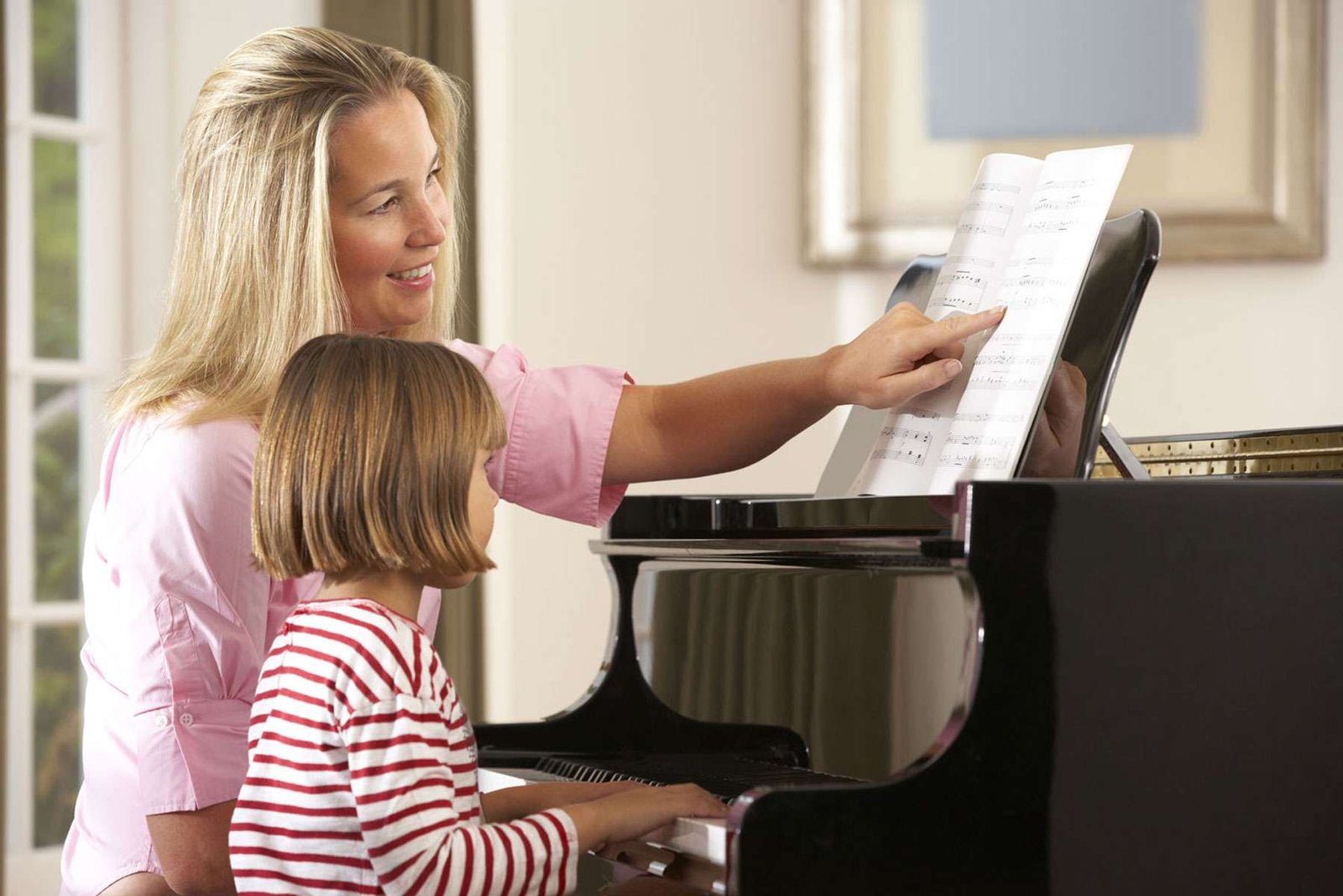 A piano tutor teaching a kid how to play a note