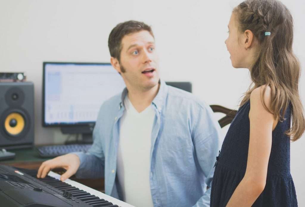 male vocal instructor teaching young girl to sing