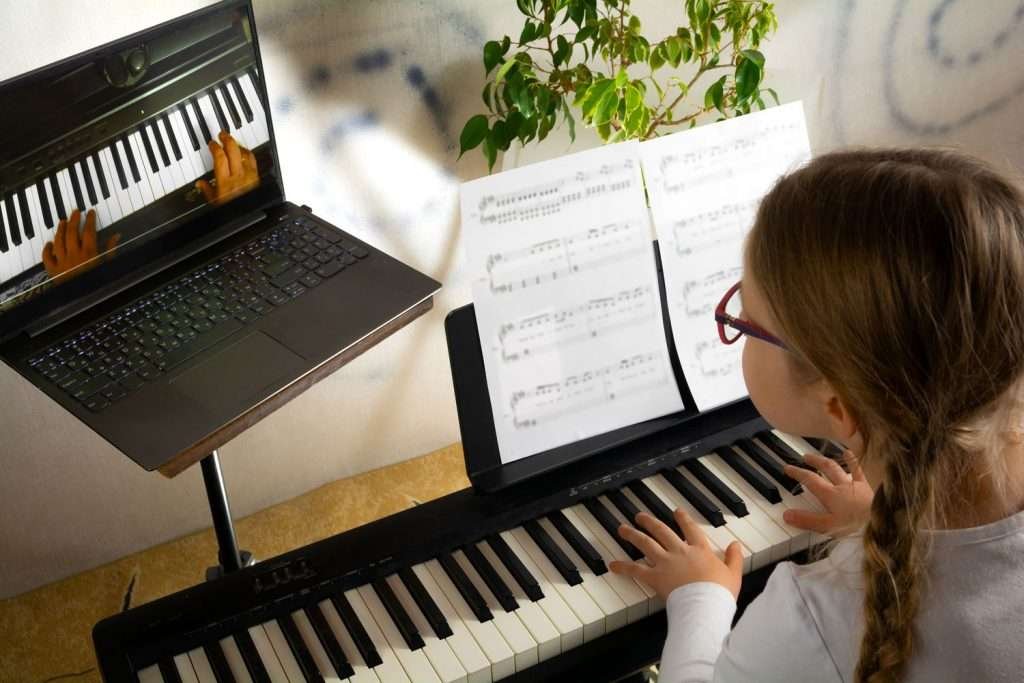 girl learning to play piano via online piano lesson