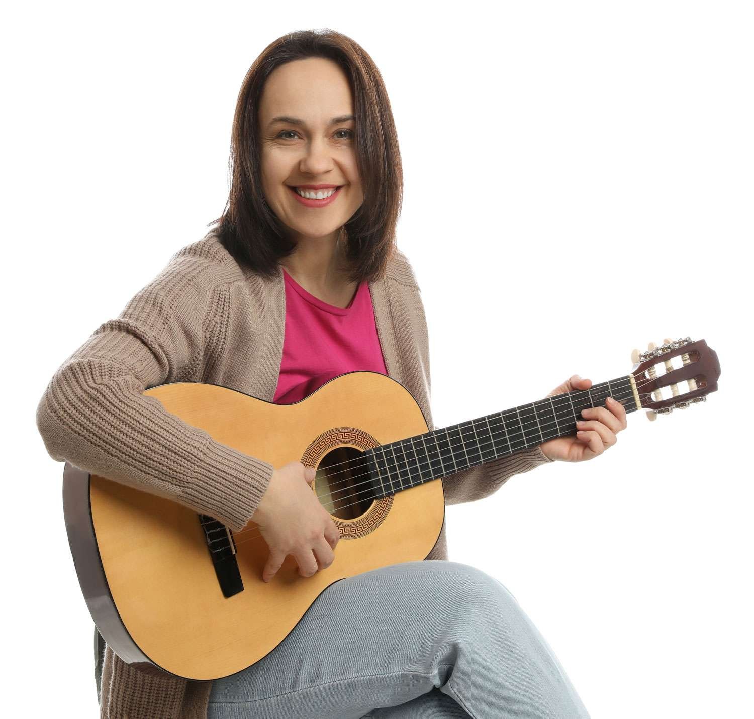 guitar teacher holding her guitar while smiling at the camera
