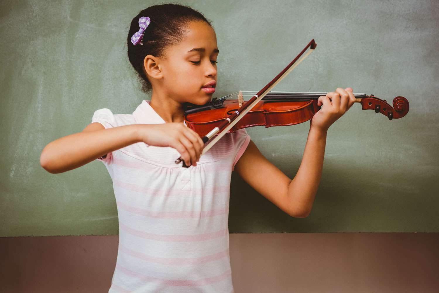 young girl plays the violin while looking at it