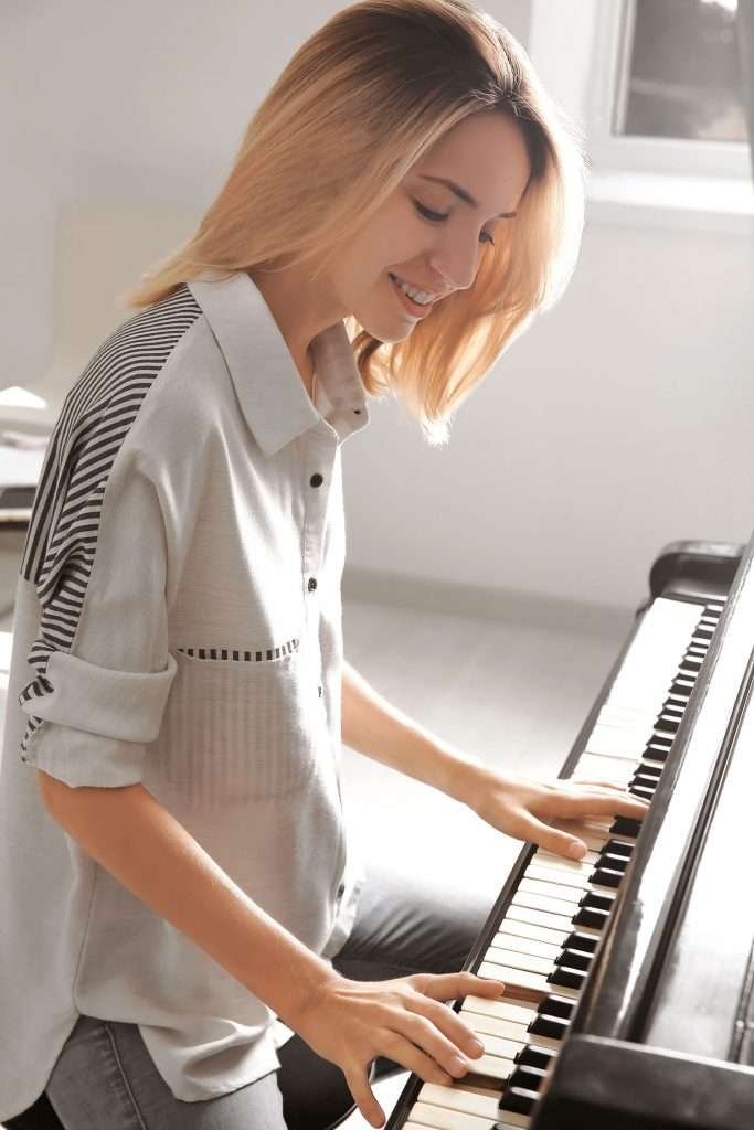 talented young woman playing piano indoors
