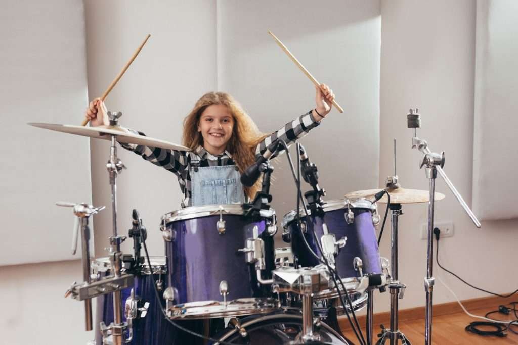 happy young girl playing the drums